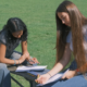 two girls writing songs in the park